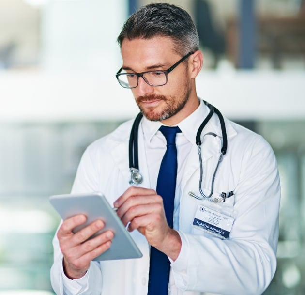 man with glasses in lab coat on tablet