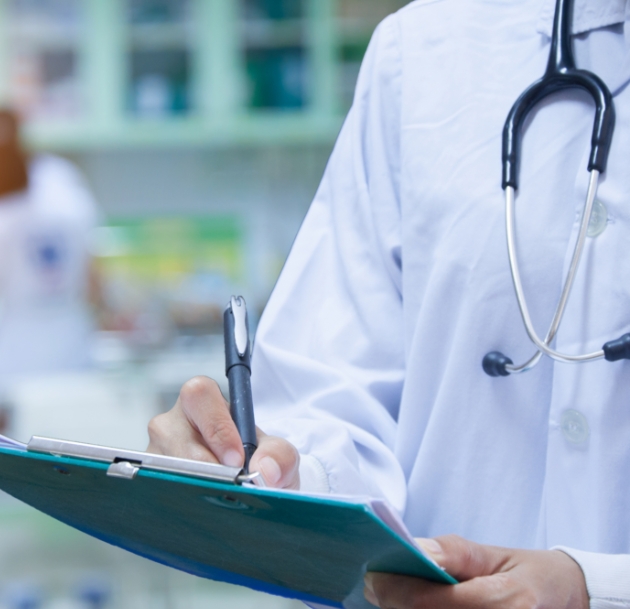 person wearing lab coat writing on clipboard